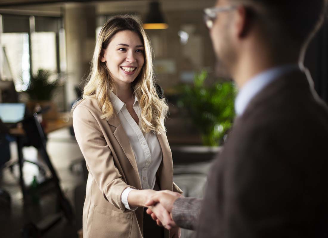 We Are Independent - Businesswoman Shakes Hands and Greets a Client in a Bustling Modern Office